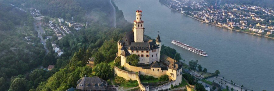 Marksburg Castle in Braubach Germany overlooking the Rhine River with a river cruise ship sailing past