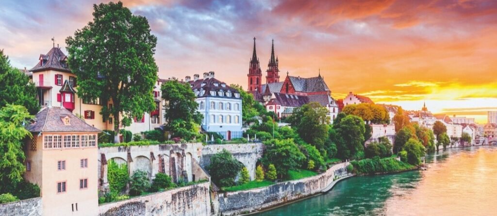 Historic Basel Switzerland skyline along the Rhine River with colorful buildings and cathedral seen from a river cruise