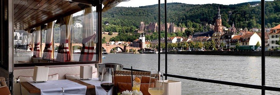 Riverside dining in Heidelberg with views of Heidelberg Castle and the Old Bridge along the Neckar River in Germany