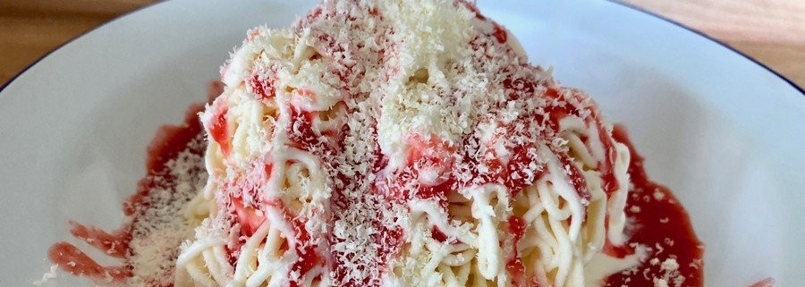 Spaghetti Eis dessert in Heidelberg with vanilla ice cream shaped like pasta topped with strawberry sauce and white chocolate shavings