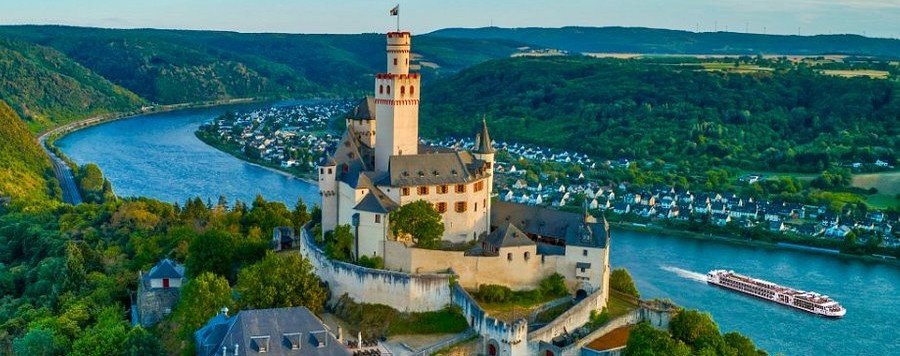 Marksburg Castle overlooking the Rhine Gorge with river cruise ship sailing below in the Upper Middle Rhine Valley Germany