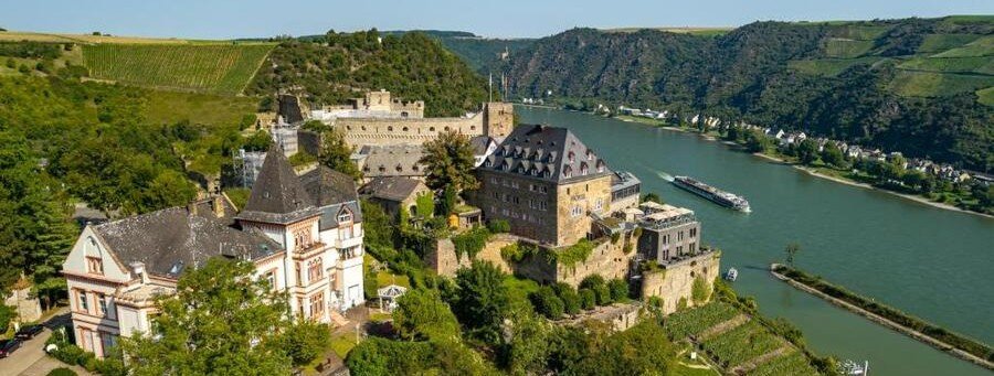 Rheinfels Castle ruins overlooking the Rhine Gorge and river cruise ship in the Upper Middle Rhine Valley Germany