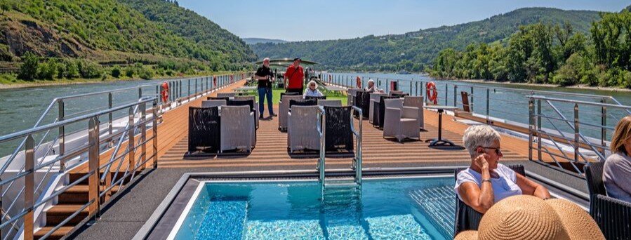 River cruise passengers relaxing on the sun deck while sailing through the Rhine Gorge in Germany